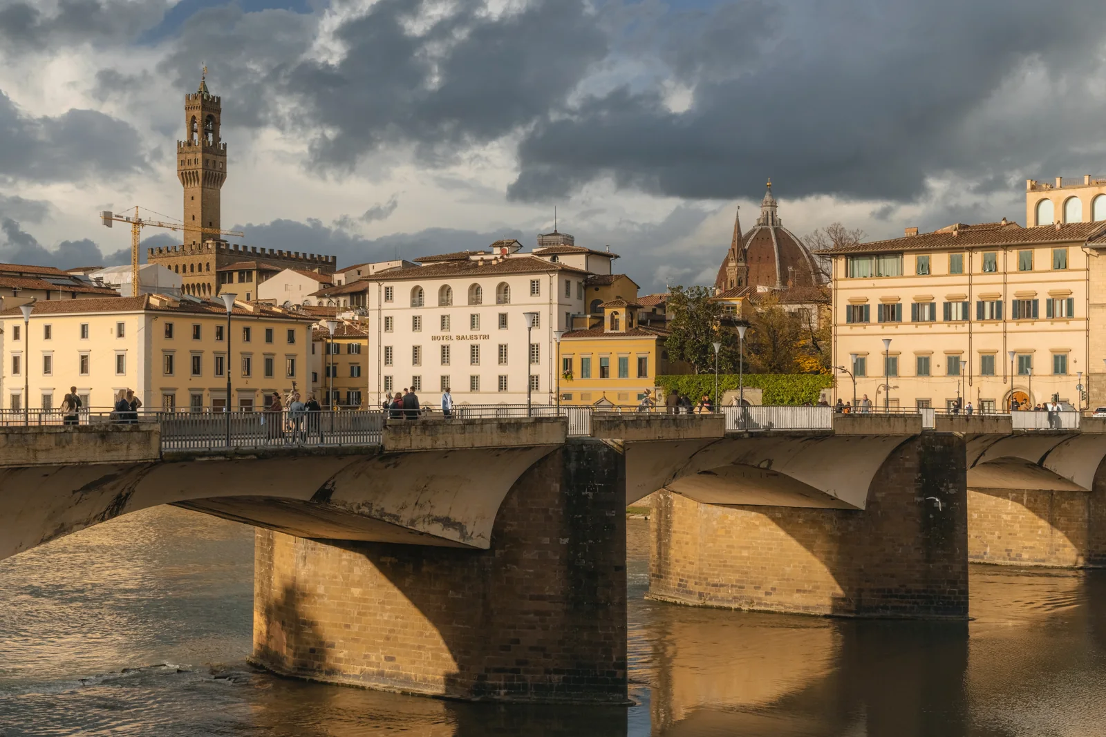 Bridge over the Arno at golden hour with the Palazzo Vecchio tower and Duomo behind