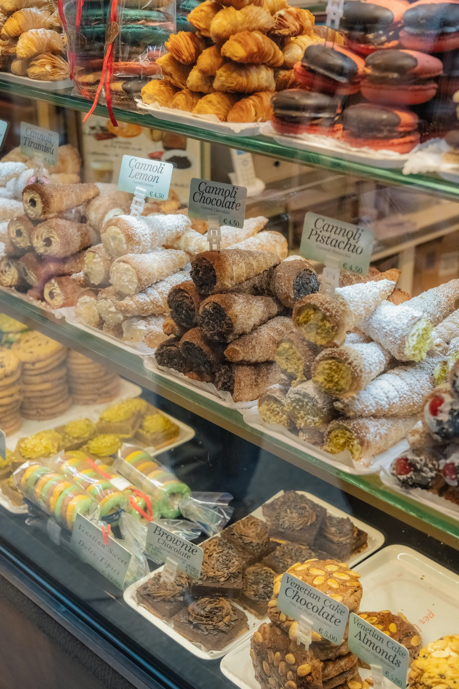 A pastry shop window stacked with cannoli, pastries and Venetian sweets