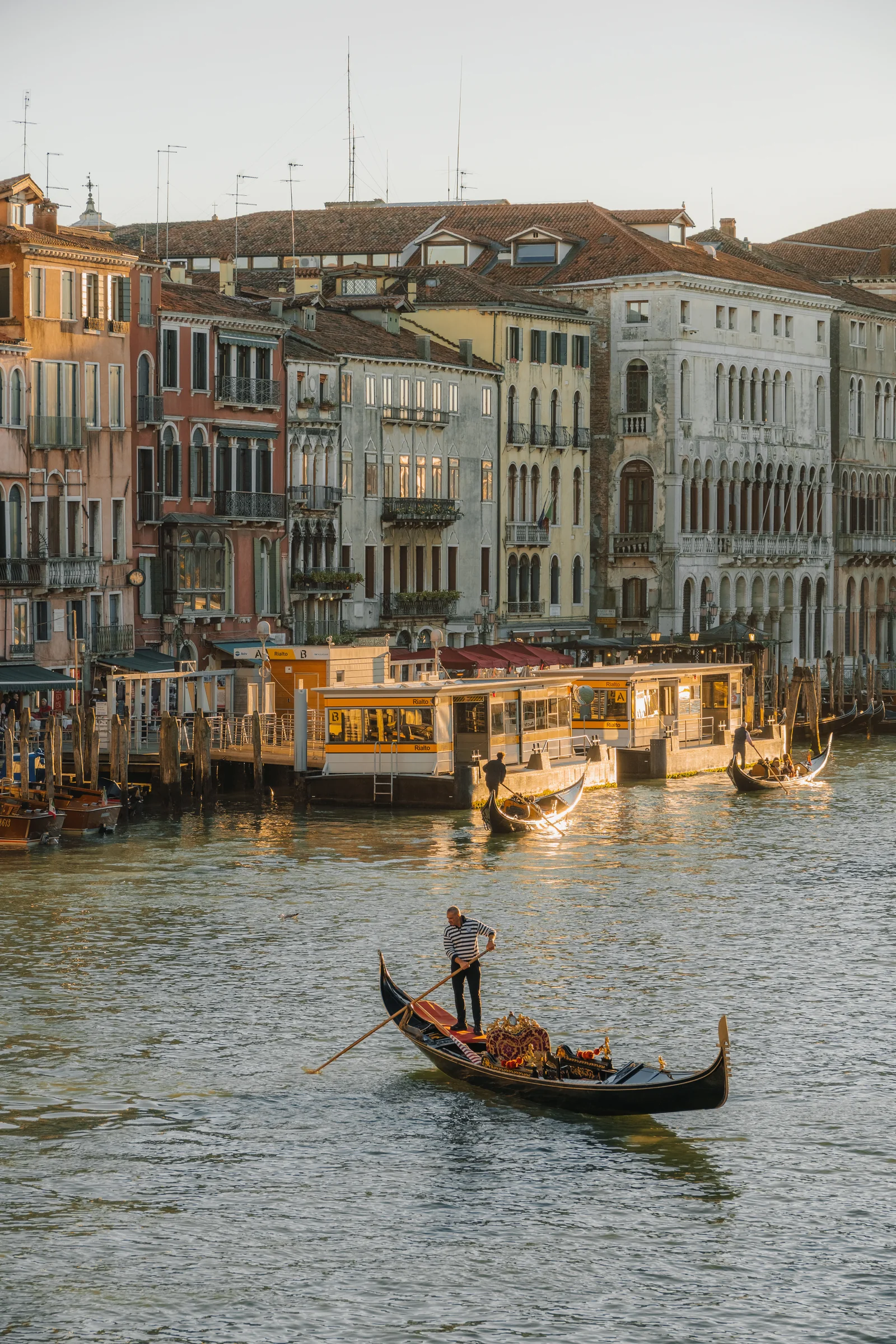 A gondolier working the Grand Canal by the Rialto stops in warm low light